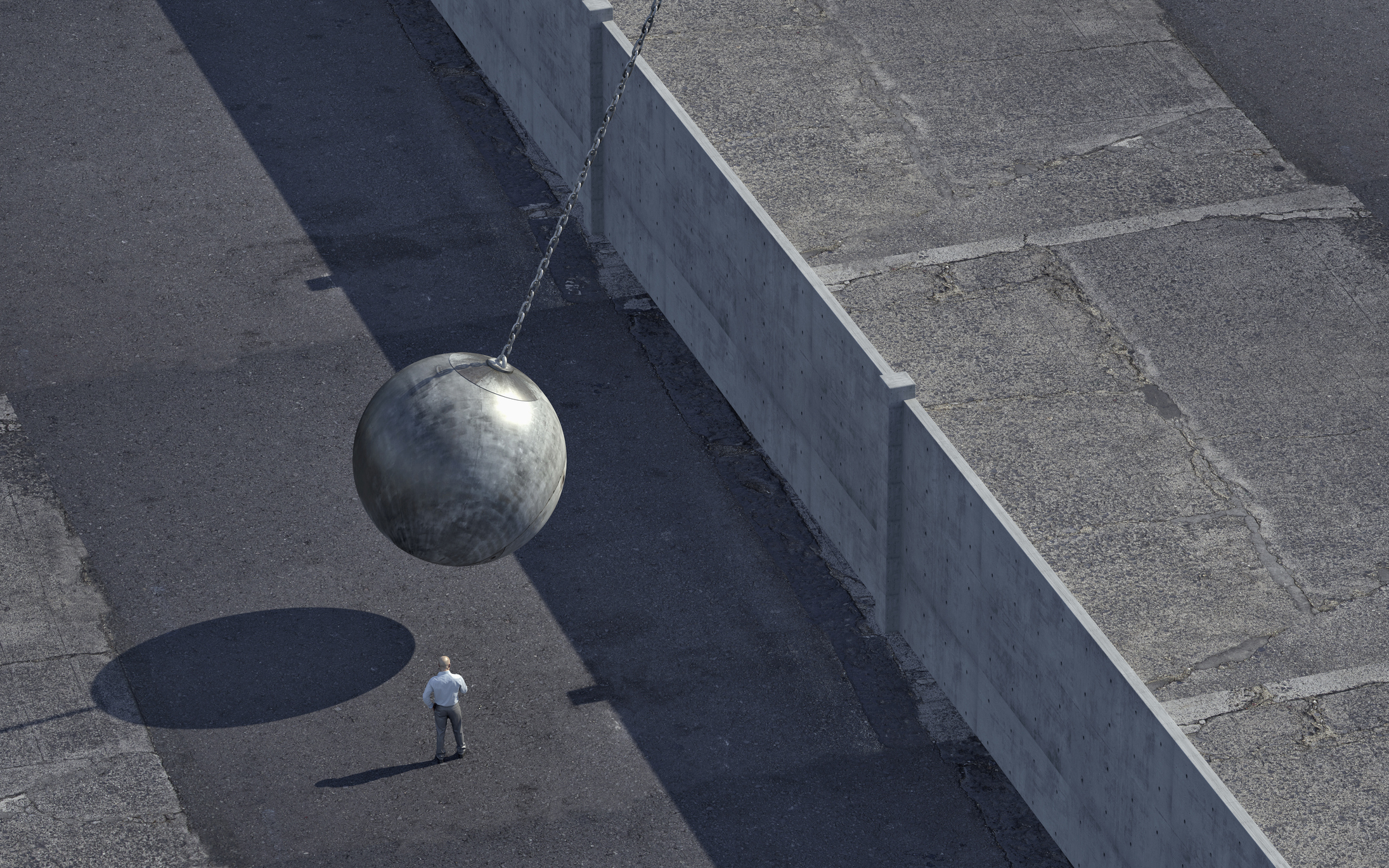 man watching wrecking ball swinging at wall