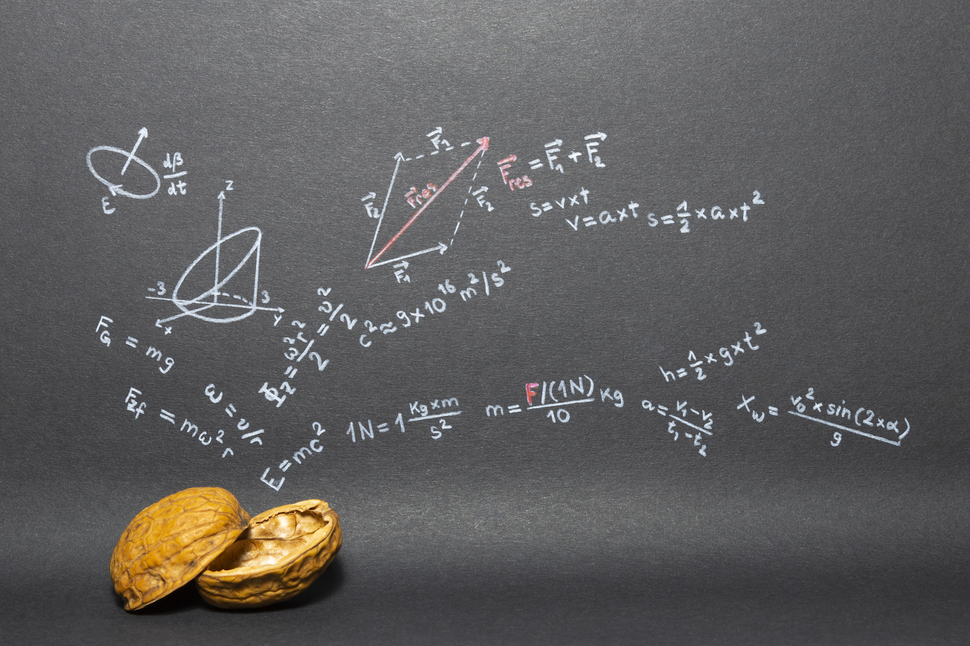 Concept of the phrase physics in a nutshell. Physics formulas drawn on black paper with walnuts