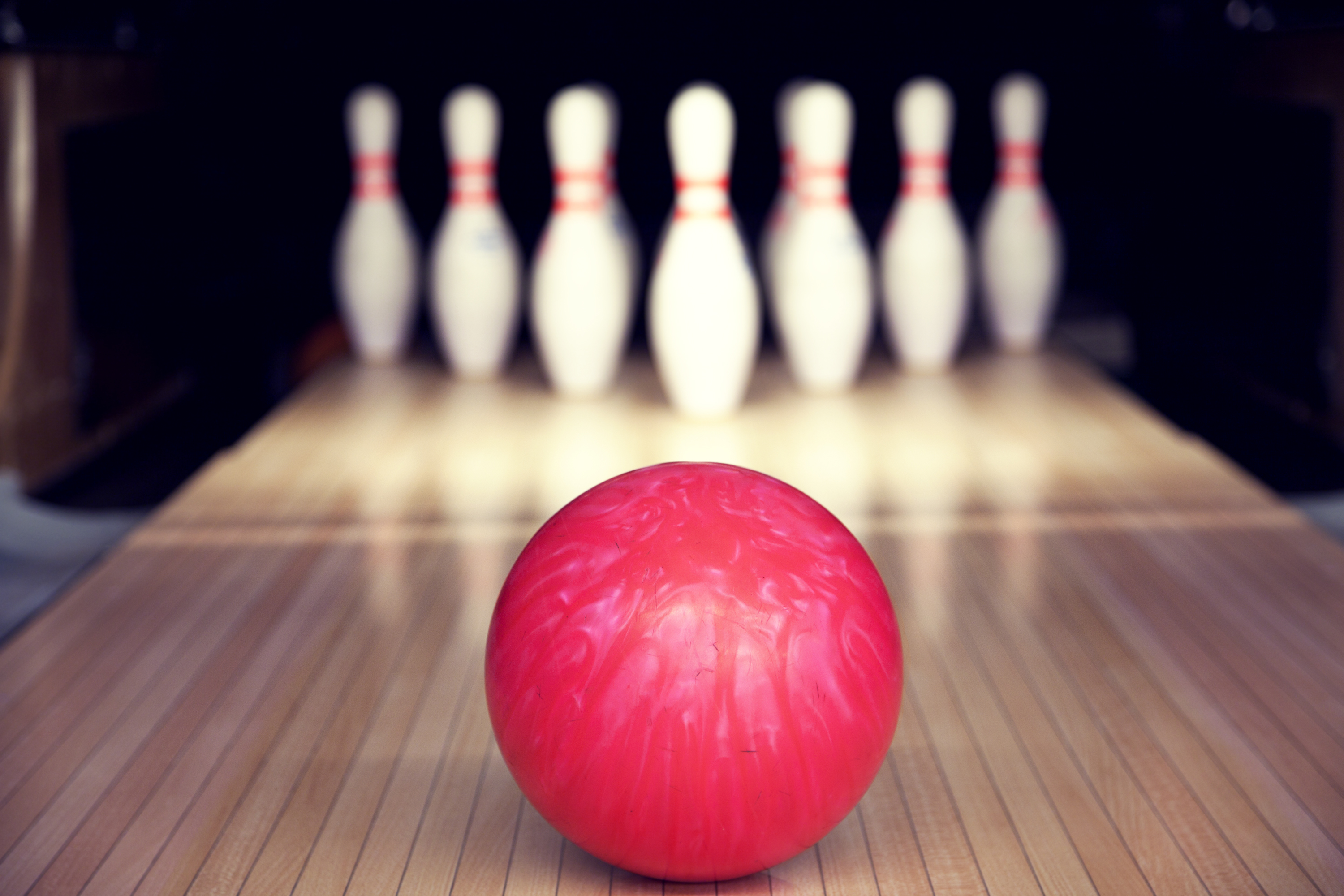 pink bowling ball rolling toward pins in bowling alley