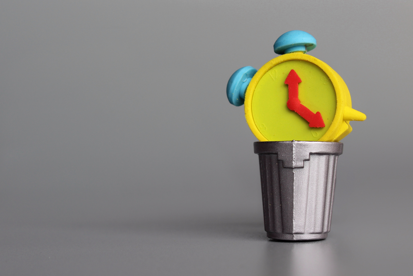 Wasting time concept. Alarm clock inside garbage can. Copy space for text.