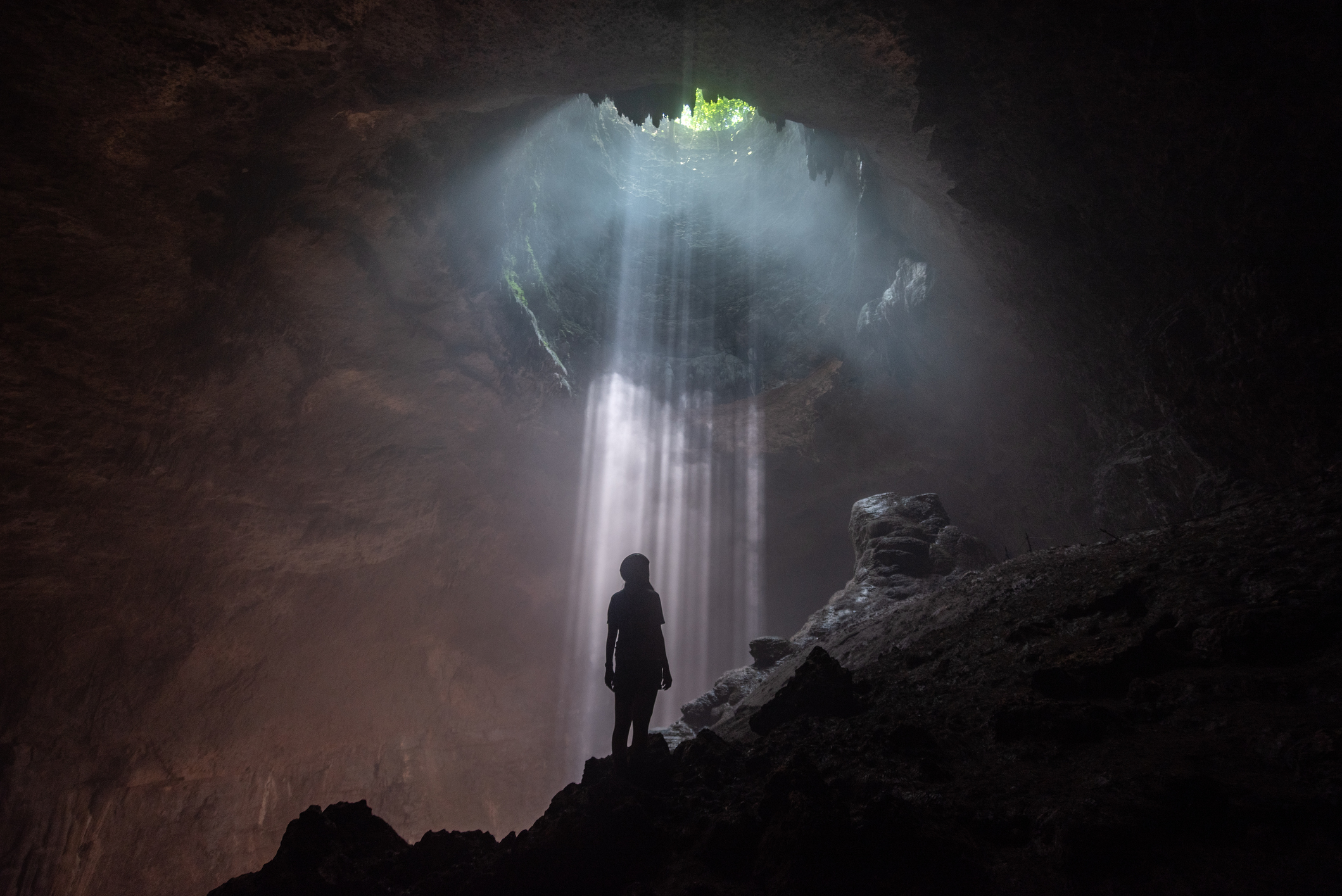 woman looking up at opening in Jomblang Cave