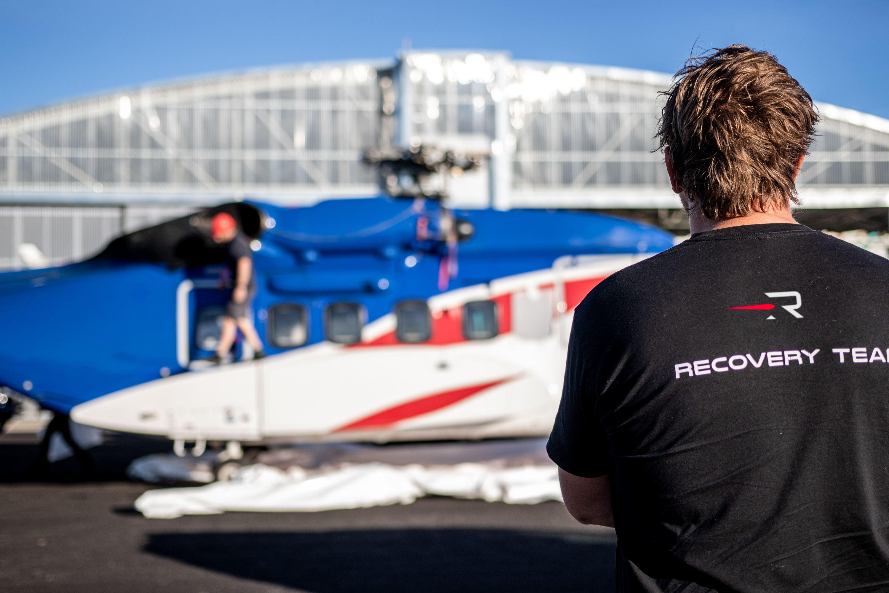 A Sikorsky helicopter ready to take off with rocket lab staff nearby.