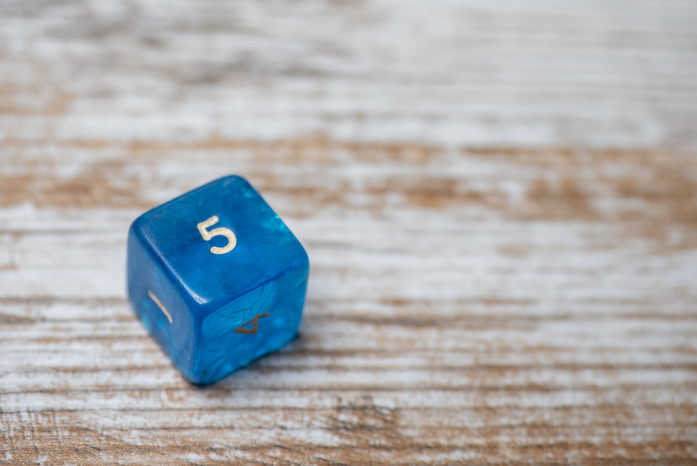 6-sided die showing the number 5 On Old Wooden Table