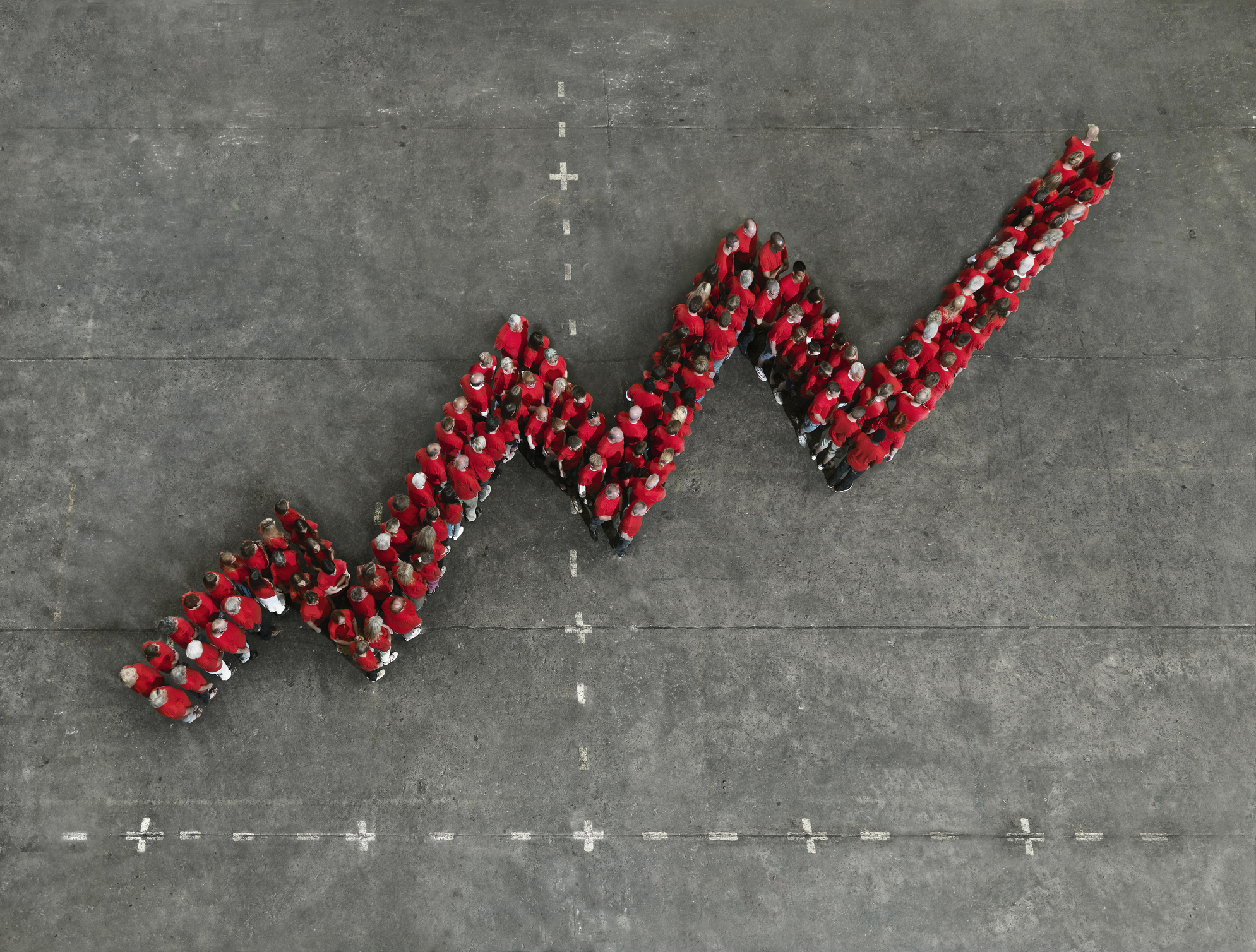 A crowd of people wearing red shirts, forming a graph shape, symbolizing product ops and contribution to product led growth