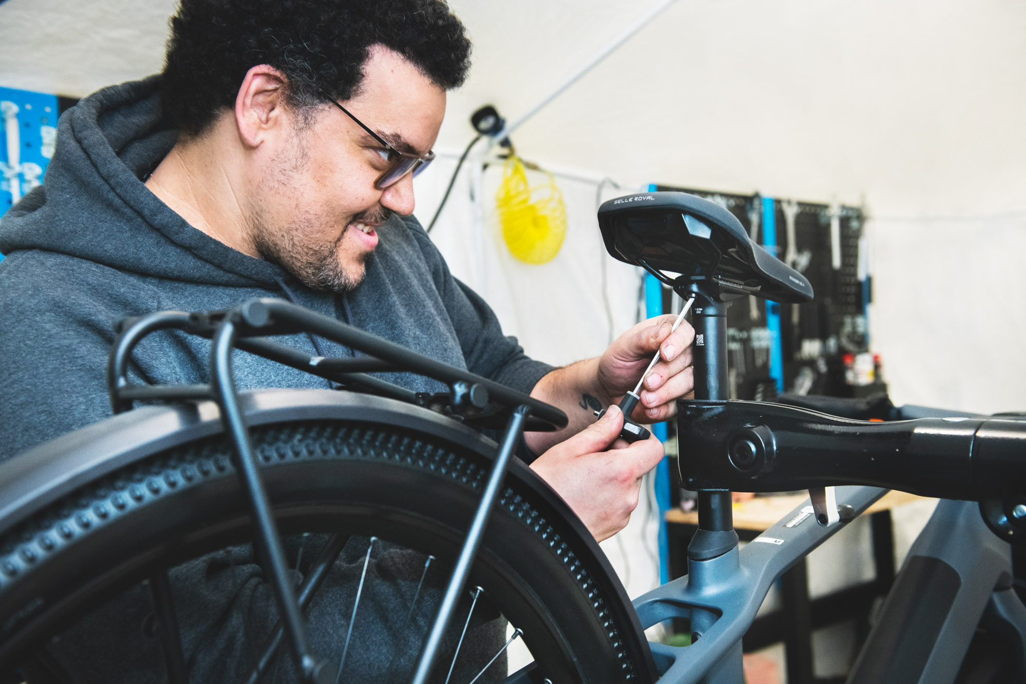 A bike repair person checking the seat of a bike