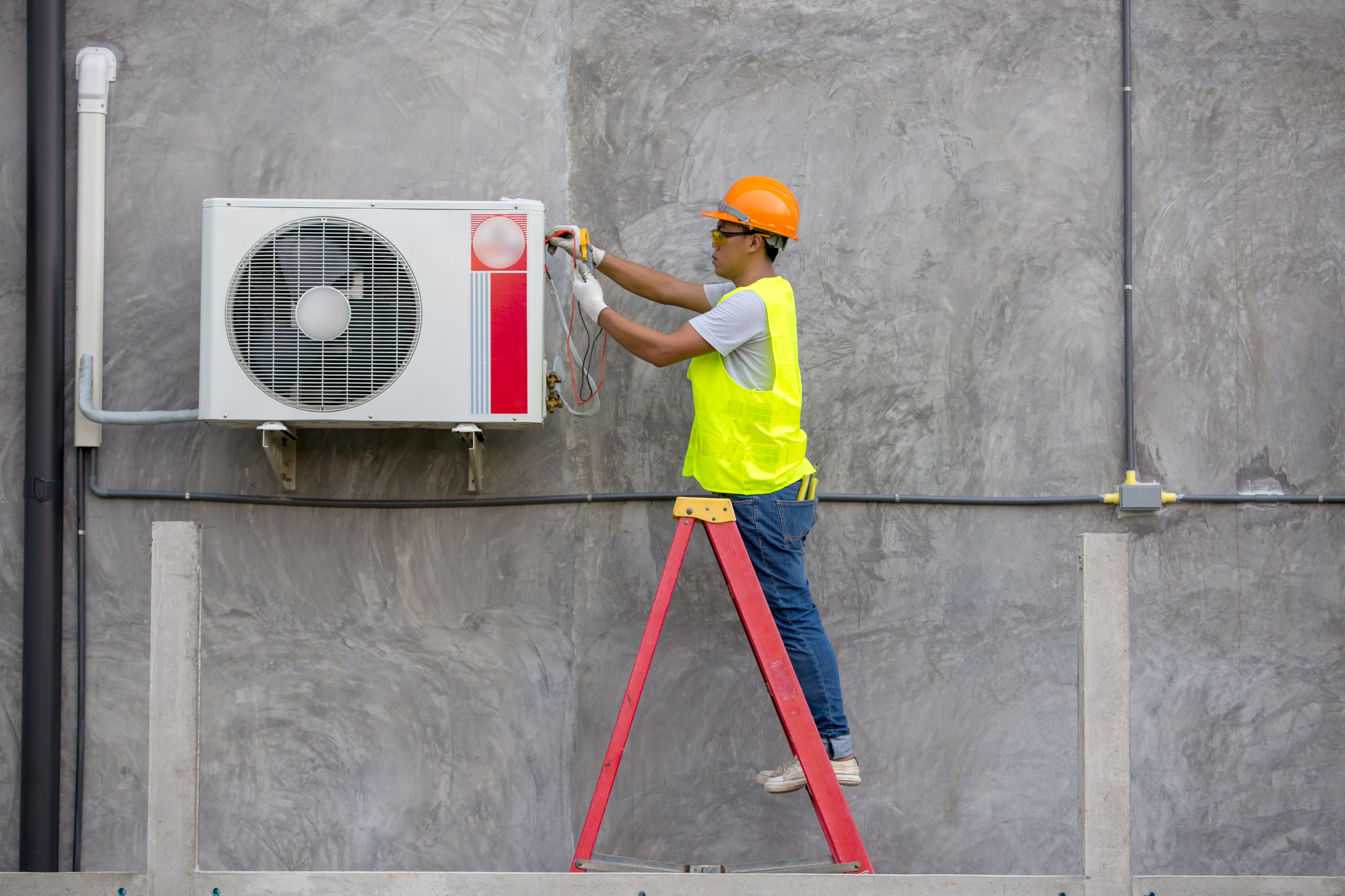 Image of an air conditioner technician service checking air conditioner on a building.