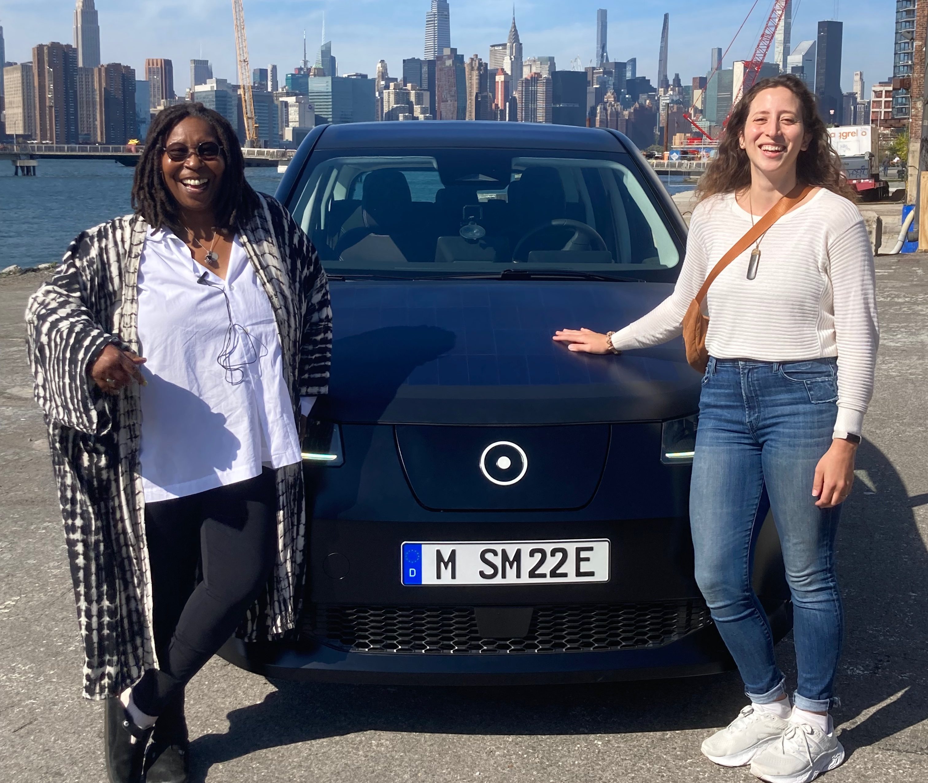 Rebecca Bellan and Whoopi Goldberg posing in front of Sono Motors Sion EV